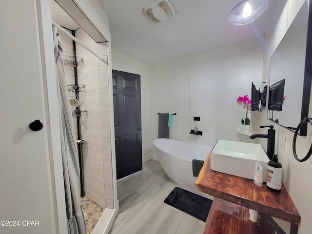 full bath with wood finished floors, a sink, visible vents, a soaking tub, and a stall shower