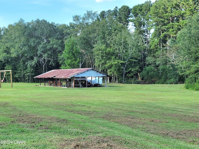 view of yard featuring a pole building, an outdoor structure, and a wooded view