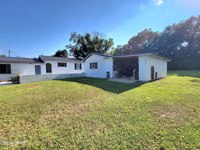 back of property featuring brick siding, metal roof, and a yard