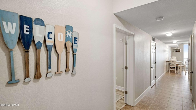 hallway featuring a textured ceiling and light tile patterned flooring