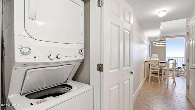 clothes washing area featuring stacked washer and clothes dryer and light tile patterned floors