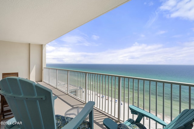 balcony with a water view and a view of the beach