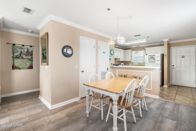 dining room featuring a textured ceiling, light tile patterned flooring, a chandelier, and ornamental molding