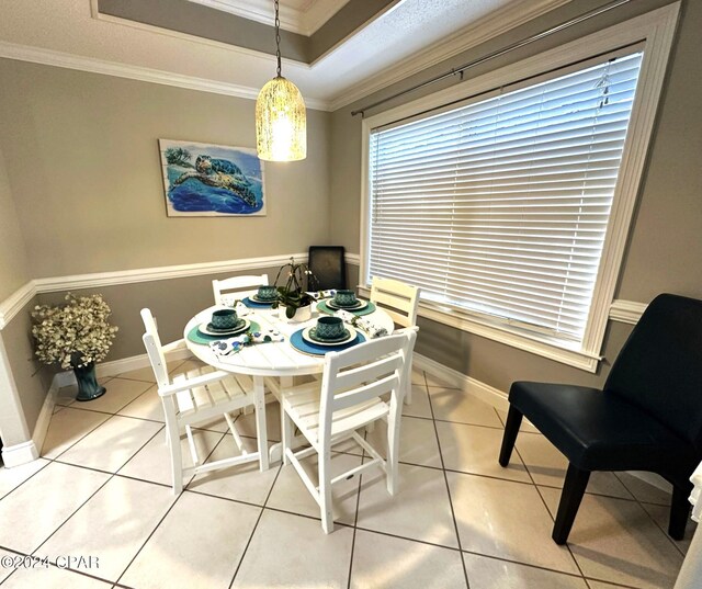 dining area featuring ornamental molding, a raised ceiling, and light tile patterned floors