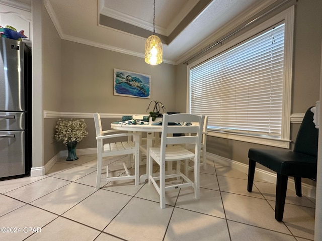 tiled dining space featuring a tray ceiling and crown molding