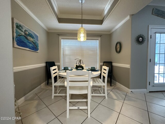 dining room featuring a textured ceiling, ornamental molding, a tray ceiling, and light tile patterned flooring