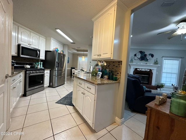 kitchen with white cabinets, backsplash, stainless steel appliances, and ceiling fan