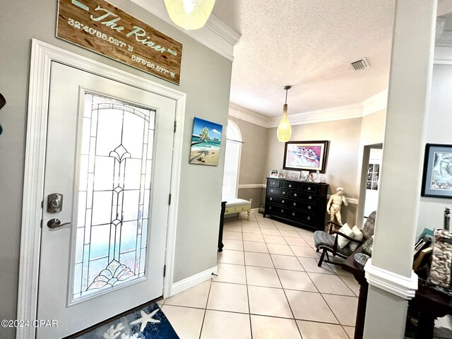 entrance foyer with ornamental molding, a textured ceiling, and light tile patterned floors