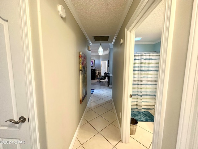 hallway featuring crown molding, a textured ceiling, and light tile patterned floors