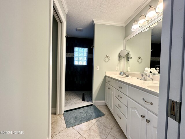 bathroom featuring a textured ceiling, ornamental molding, dual bowl vanity, and tile patterned floors