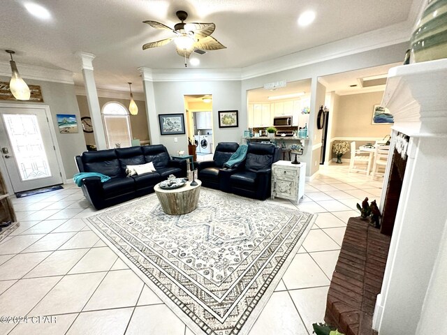 tiled living room with crown molding, a textured ceiling, ornate columns, and ceiling fan