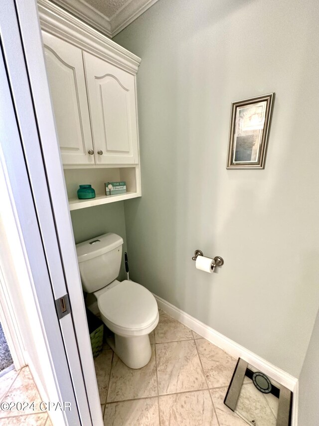 bathroom with tile patterned flooring, toilet, and crown molding