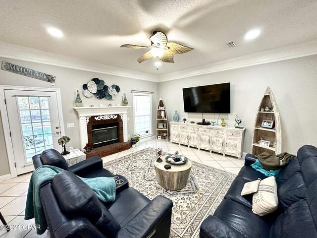 tiled living room featuring a textured ceiling, crown molding, ceiling fan, and a brick fireplace