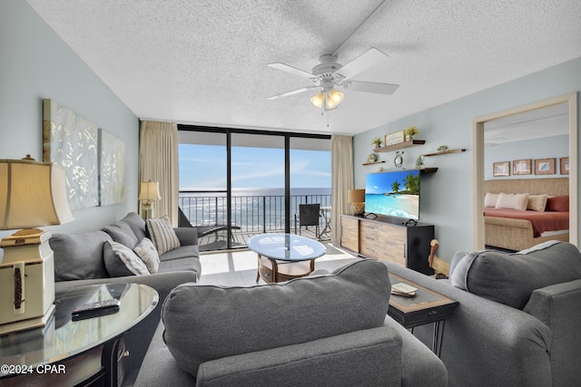 living room with a wealth of natural light, ceiling fan, a textured ceiling, and a wall of windows