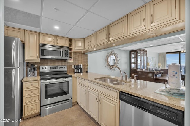 kitchen with sink, a paneled ceiling, decorative backsplash, light tile patterned floors, and appliances with stainless steel finishes