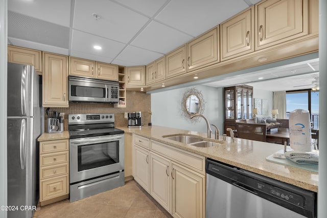 kitchen with appliances with stainless steel finishes, tasteful backsplash, sink, light tile patterned floors, and light stone countertops