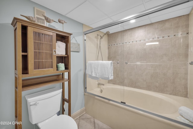 bathroom featuring a paneled ceiling, tile patterned flooring, toilet, and bath / shower combo with glass door