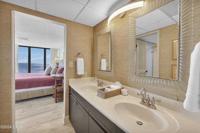 bathroom with hardwood / wood-style floors, vanity, a wall of windows, and a drop ceiling