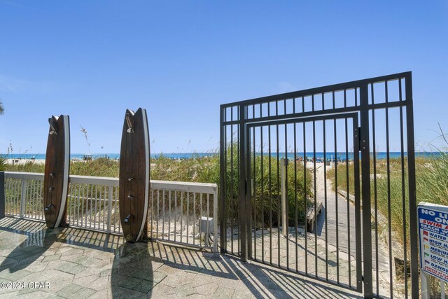 view of gate with a water view and a view of the beach