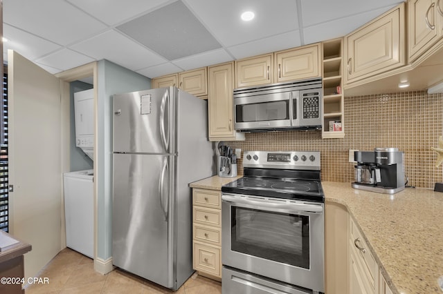 kitchen featuring decorative backsplash, a paneled ceiling, stainless steel appliances, and stacked washer and clothes dryer