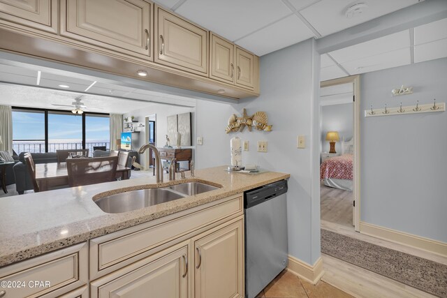 kitchen featuring a paneled ceiling, dishwasher, sink, ceiling fan, and light stone countertops