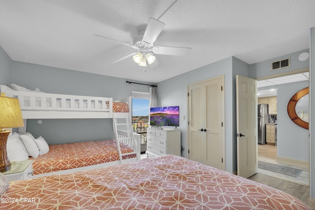 bedroom with stainless steel fridge, a closet, ceiling fan, and a textured ceiling