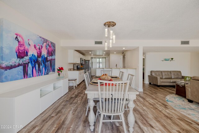 dining area with light hardwood / wood-style floors and a textured ceiling