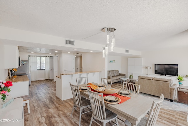 dining space with light hardwood / wood-style floors and a textured ceiling