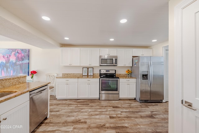 kitchen featuring light stone countertops, appliances with stainless steel finishes, light hardwood / wood-style floors, and white cabinetry