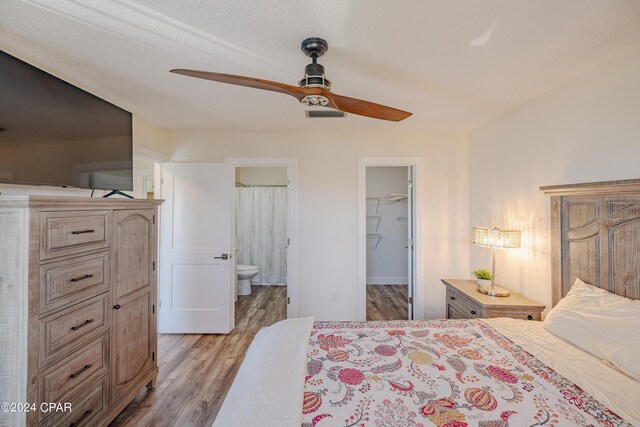 bedroom with ceiling fan, ensuite bathroom, a closet, a spacious closet, and light hardwood / wood-style floors