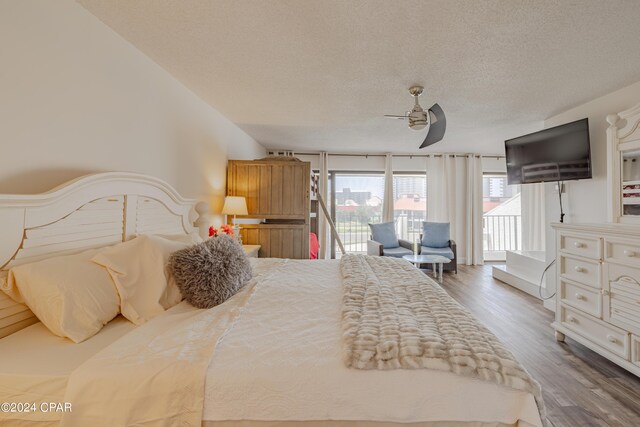 bedroom featuring access to outside, a textured ceiling, dark wood-type flooring, and ceiling fan