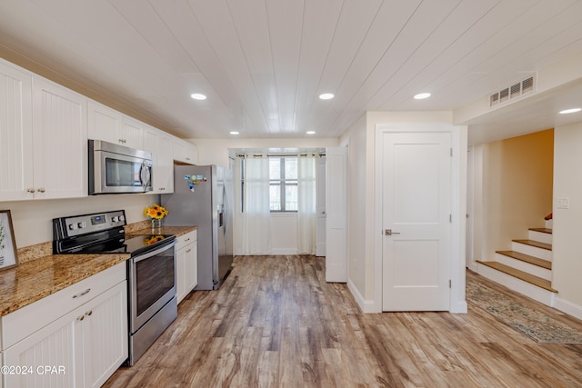 kitchen featuring light stone counters, white cabinets, stainless steel appliances, and light wood-type flooring