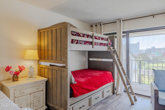 bedroom featuring access to outside, a textured ceiling, and light wood-type flooring