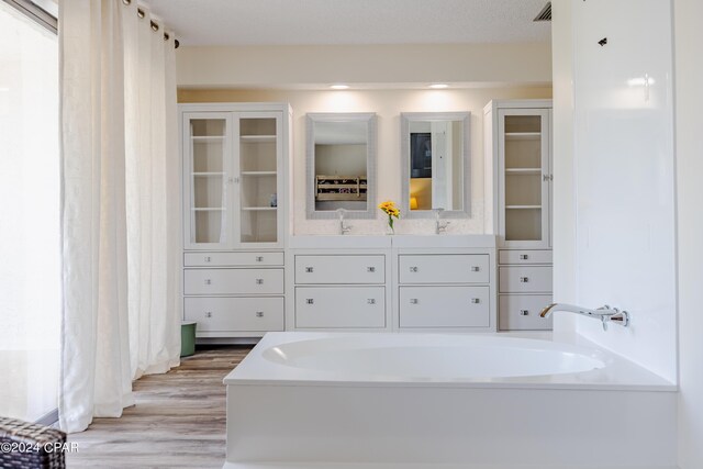 bathroom featuring a textured ceiling, wood-type flooring, vanity, and a washtub