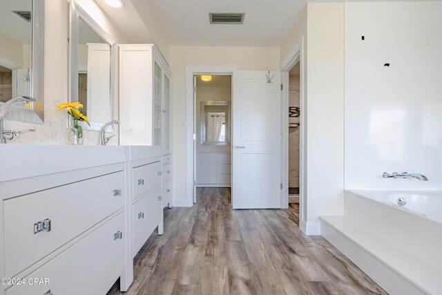 bathroom with a bath, a textured ceiling, vanity, and hardwood / wood-style floors