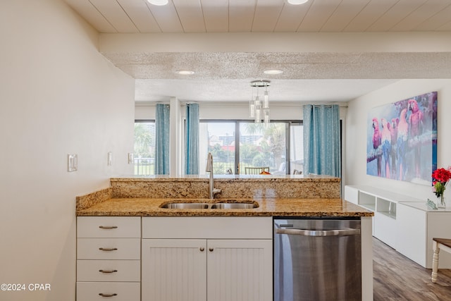 kitchen with hanging light fixtures, white cabinets, hardwood / wood-style flooring, stainless steel dishwasher, and sink