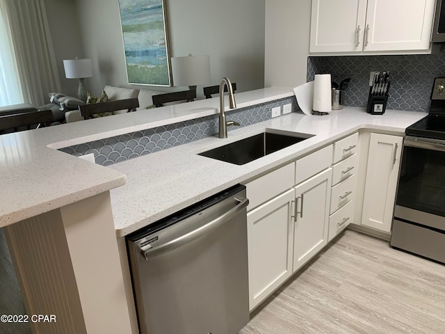 kitchen featuring light stone counters, backsplash, light wood-type flooring, stainless steel appliances, and sink