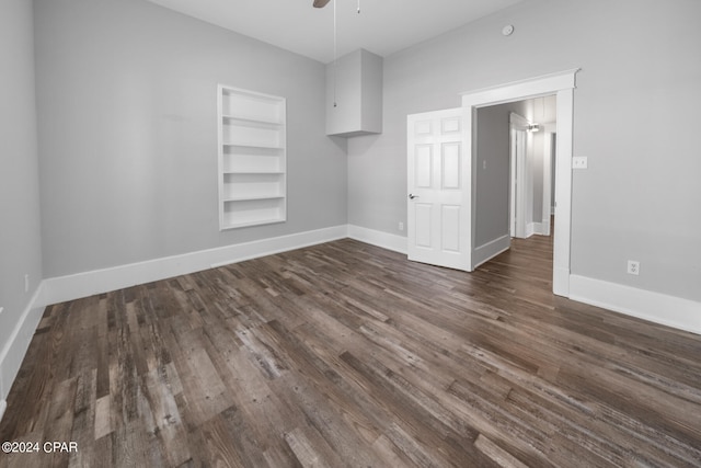 empty room with ceiling fan, built in shelves, and wood-type flooring