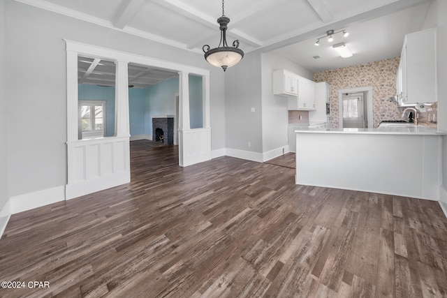 unfurnished living room featuring beamed ceiling, coffered ceiling, sink, and dark wood-type flooring