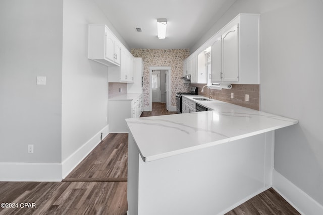 kitchen with kitchen peninsula, stainless steel range, dark hardwood / wood-style flooring, and decorative backsplash