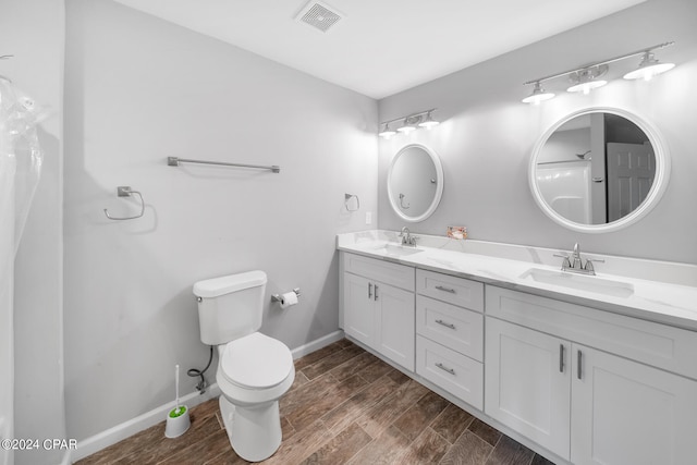 bathroom featuring dual vanity, wood-type flooring, and toilet