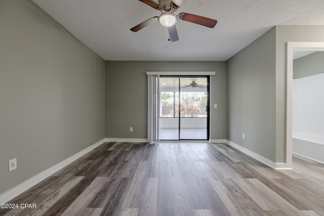 empty room with ceiling fan, wood-type flooring, and a textured ceiling