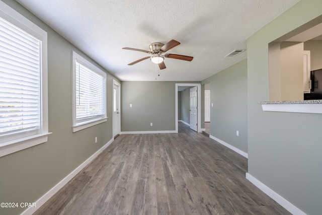 empty room featuring a textured ceiling, dark hardwood / wood-style floors, and ceiling fan