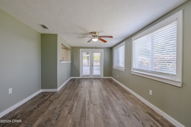 unfurnished room with french doors, a textured ceiling, wood-type flooring, and ceiling fan