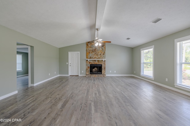 unfurnished living room with vaulted ceiling with beams, hardwood / wood-style floors, a textured ceiling, a fireplace, and ceiling fan