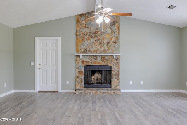 unfurnished living room featuring hardwood / wood-style flooring, a stone fireplace, vaulted ceiling, and ceiling fan