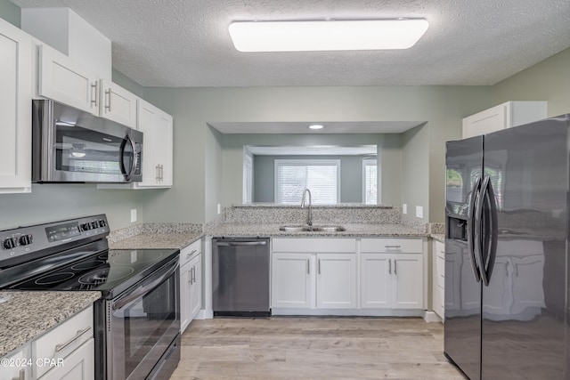 kitchen featuring stainless steel appliances, sink, light wood-type flooring, and white cabinets