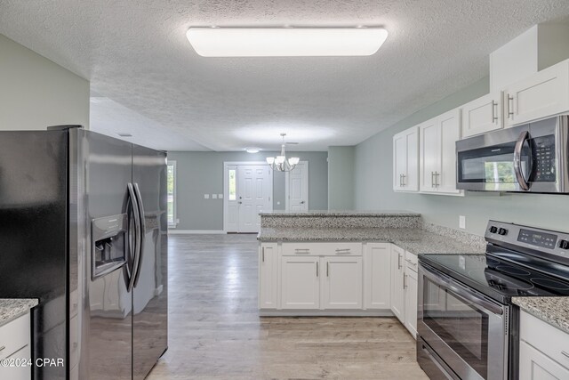 kitchen with a textured ceiling, white cabinetry, light hardwood / wood-style flooring, and stainless steel appliances