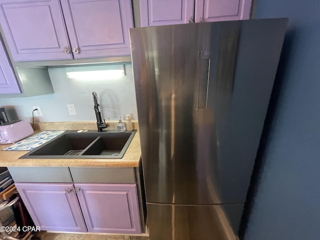 kitchen with light countertops, freestanding refrigerator, and a sink