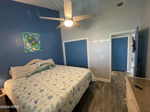 bedroom featuring baseboards, visible vents, a high ceiling, dark wood-style flooring, and a closet